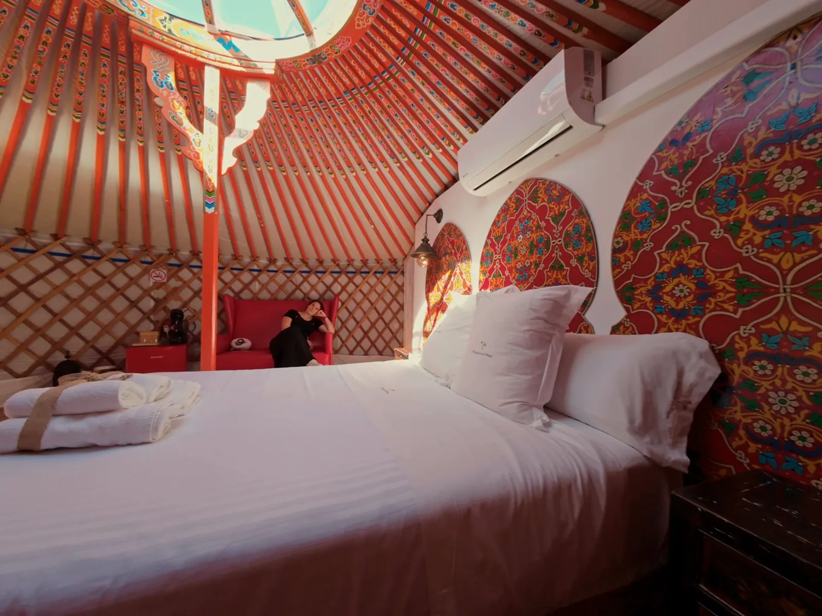 El interior rojo de la Yurta Fuego, con la cama bajo los arcos pintados a mano