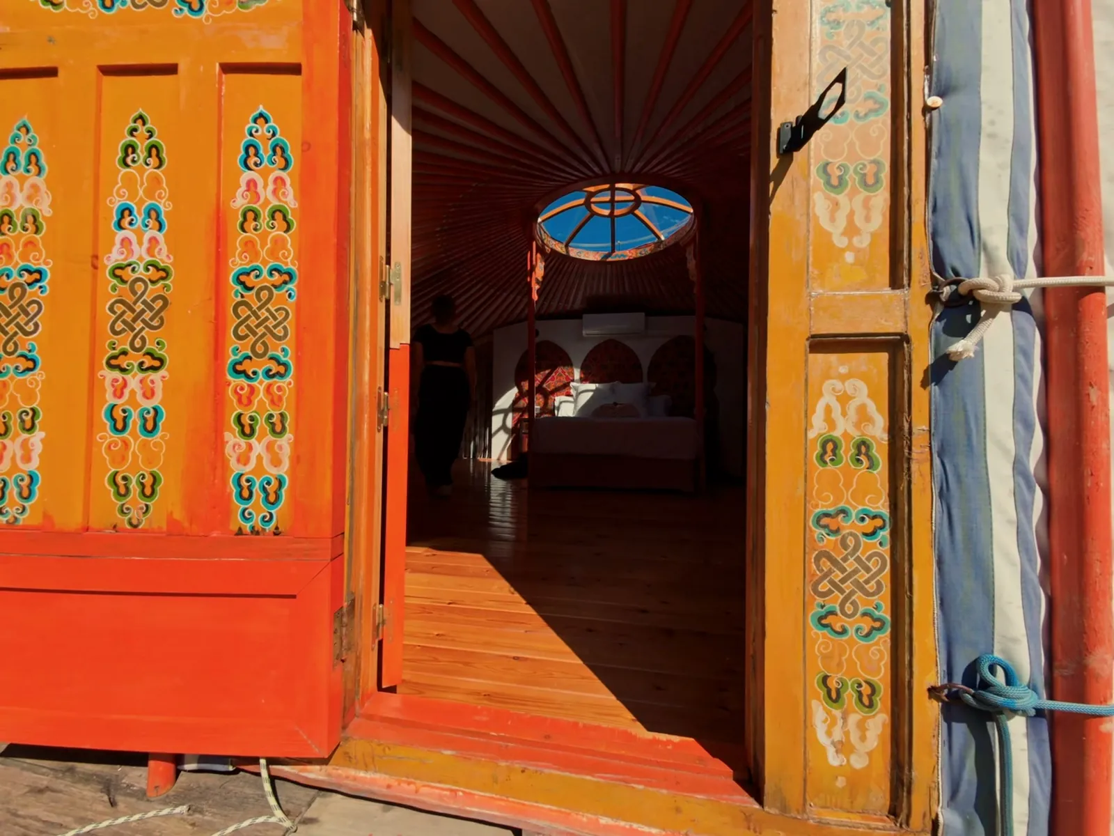 La puerta naranja pintada a mano de la Yurta Fuego, abierta