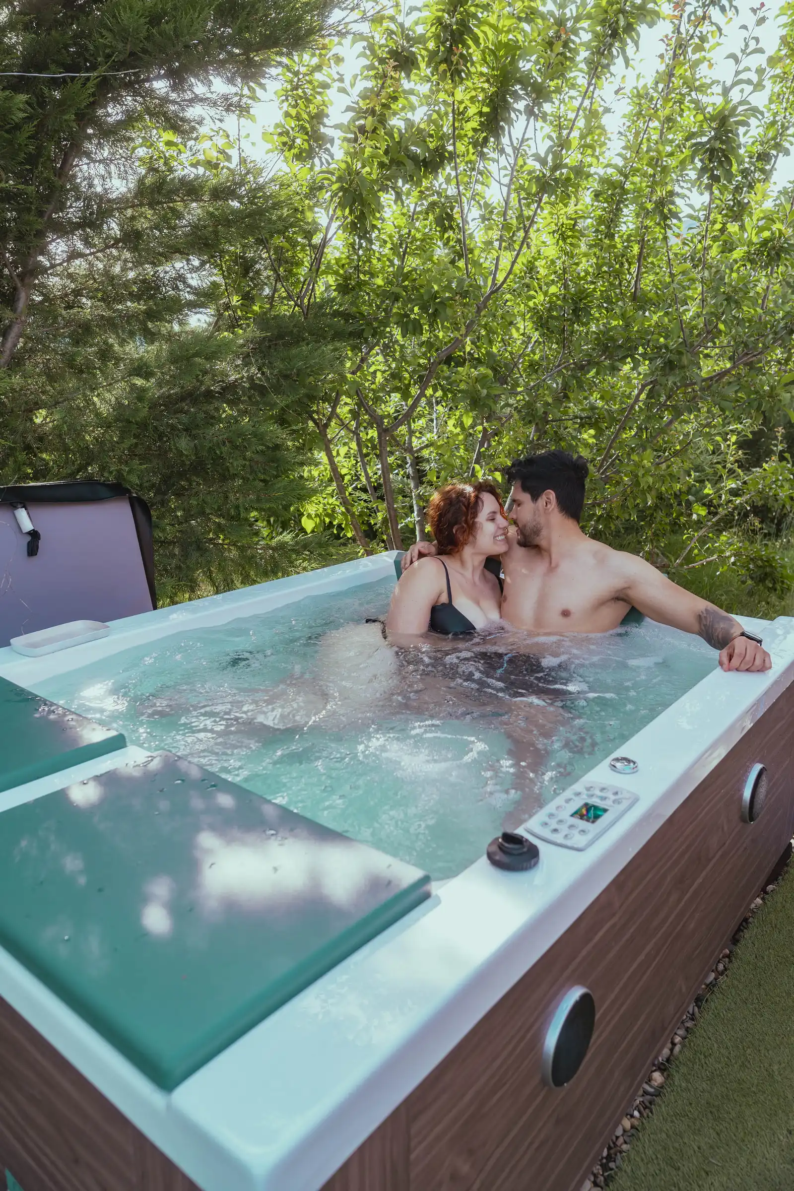 Una pareja dentro del jacuzzi de la terraza del Sky Dome, a punto de besarse, rodeada de árboles verdes