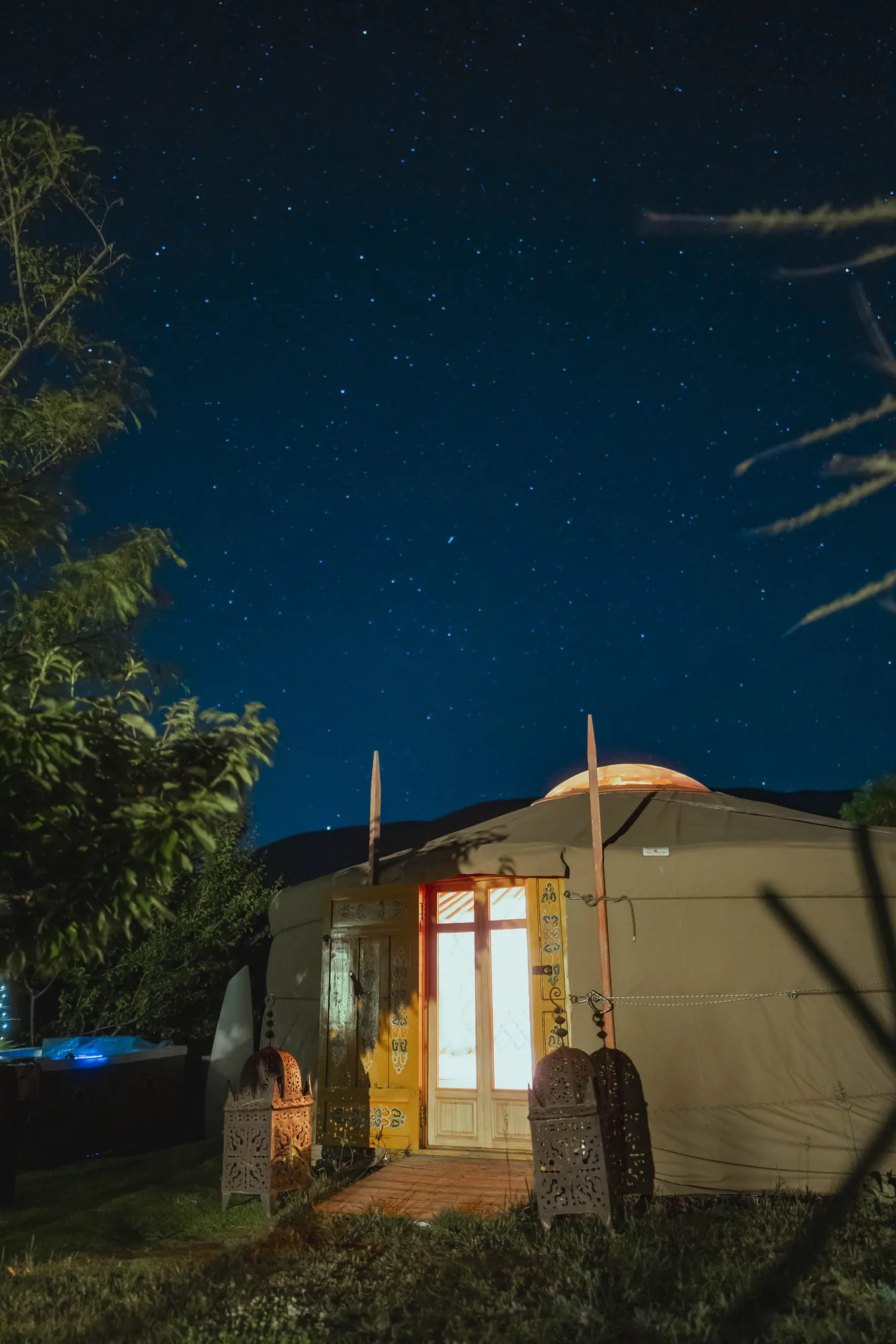La yurta iluminada por dentro con la puerta abierta, bajo el cielo estrellado del Valle del Jerte